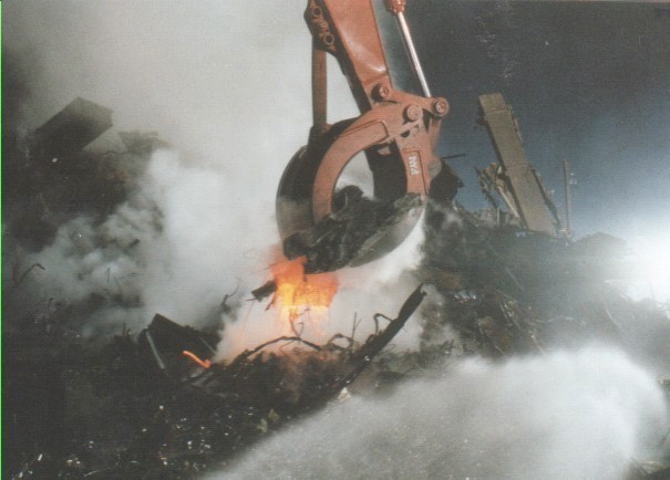 Figure 61. Heavy machinery digging into debris pile exhibiting athermal aerosol emission, with hydraulic cylinders and lines in direct contact, demonstrating low-temperature material state