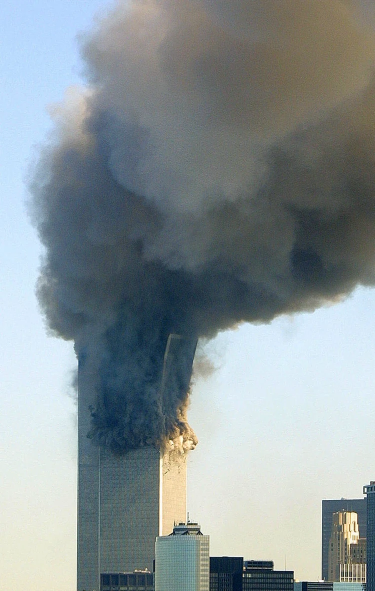 Figure 20. (9/11/2001). WTC2 top block tilting eastward as rigid structure, beginning to transition into dust cloud before ground impact, showing mid-air phase change.
<br>
- Photo by Robert Spencer / AP