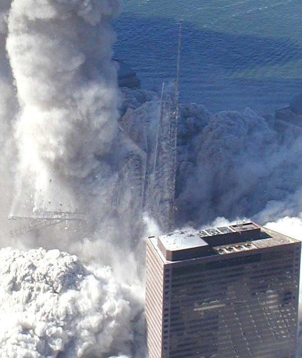 Figure 7. (9/11/2001) WTC1 steel core columns remaining upright after surrounding building aerosolization, showing the spire steel beams disintegrating into dust.
<br>
- Photo by Det Greg Semendinger, NYC Police Aviation Unit
