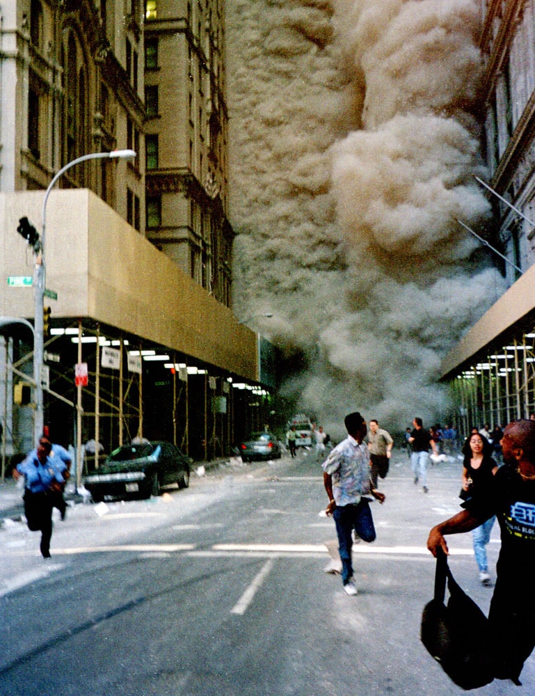 Figure 89. (9/11/01) A wall of dust moves down Broadway toward Pine Street from WTC2, at least ten stories high, maintaining height and verticality with uniform density from street level to top, demonstrating non-settling flow<br>- Image by Kelly Price/REUTERS