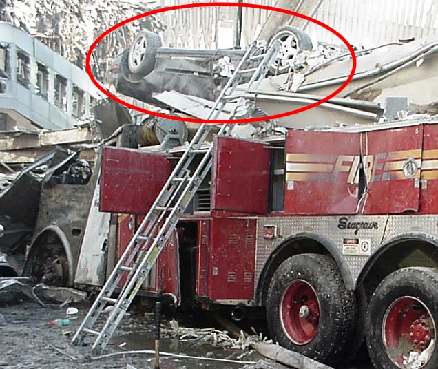 Figure 55. Overturned sedan on wreckage with Seagrave fire truck in background; vehicle displacement evidence.