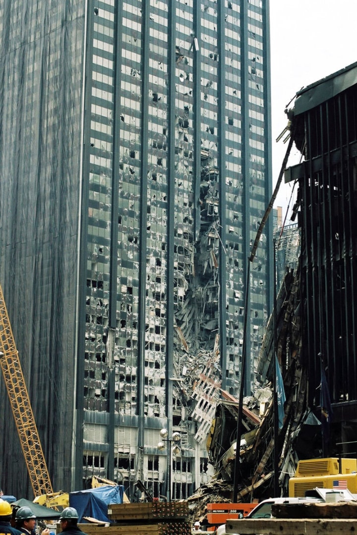 Figure 73. (09/27/2001) Bankers Trust building showing large circular gash with prefabricated perimeter column assembly hanging suspended, demonstrating impedance mismatch. <br>- Photo by Bri Rodriguez/FEMA News