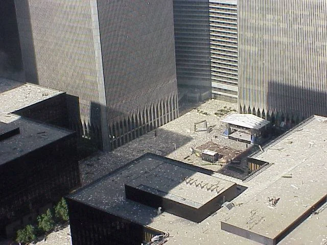 Figure 26. (9/11/01) WTC courtyard view of Austin J. Tobin Plaza during 9/11. Light debris covers the rooftops of WTC4 (left) and WTC5 (right). WTC3 in between the towers. <br>- Photo by Natasha Sealy-Fraser