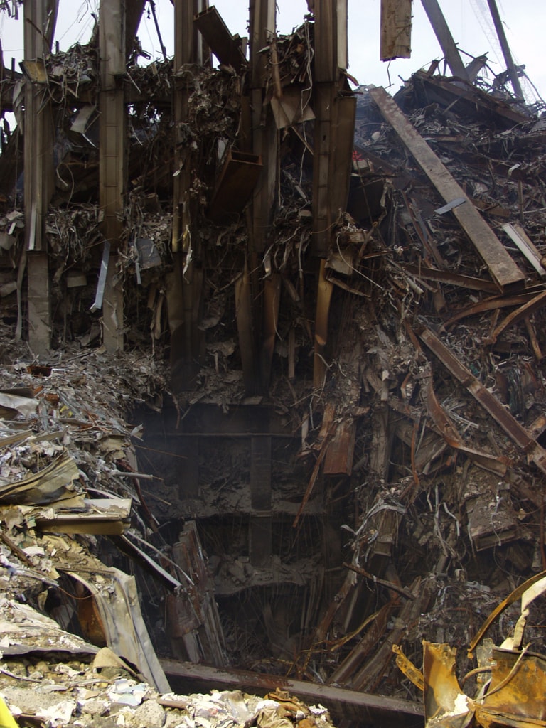 Figure 103. (9/21/01)Liberty Street Hole #1 adjacent to WTC2 and is through the sidewalk and pavement, revealing steel columns with sinusoidal deformation, showing wavy appearance as if unfolded.<br>- Image by FEMA
