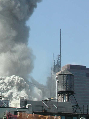 Figure 8. WTC1 steel core columns beginning to disintegrate from the top. WTC7 and water tower in the foreground.