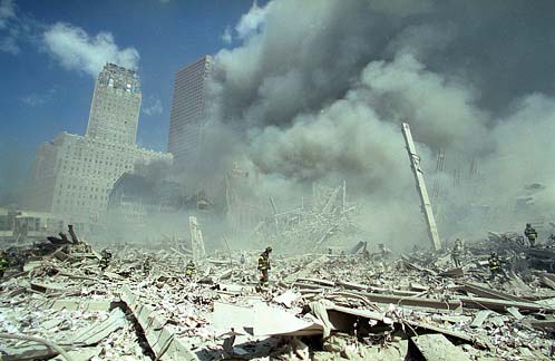 Figure 19. (9/11/2001) Panoramic view looking north-northeast directly in front of where WTC1 stood, showing vast open space with minimal debris pile, demonstrating volumetric mass deficit. WTC7 in the background at this point.
   <br>
   - Photo by James Nachtwey/Time